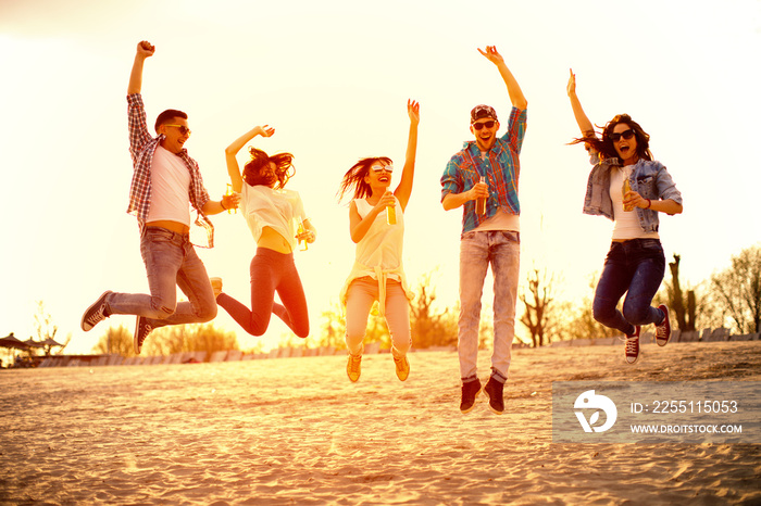 Happy young people having fun on the beach and drinking beer