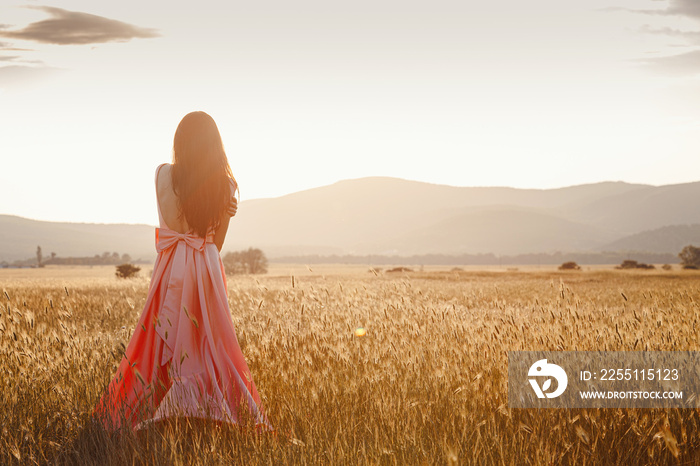 girl dancing in a field in a beautiful pink dress at sunset