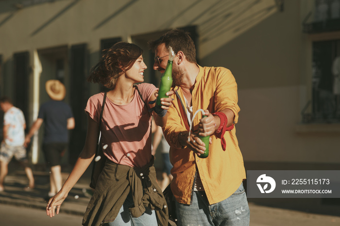 Young couple dancing on the street and opening beer