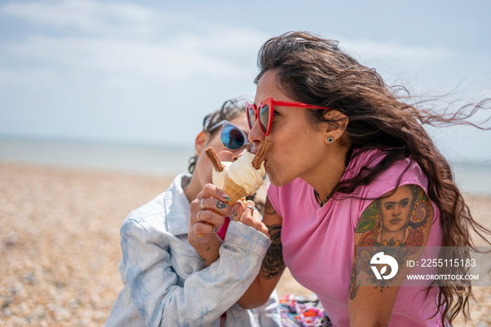 Mother and daughter (8-9) eating ice cream on beach
