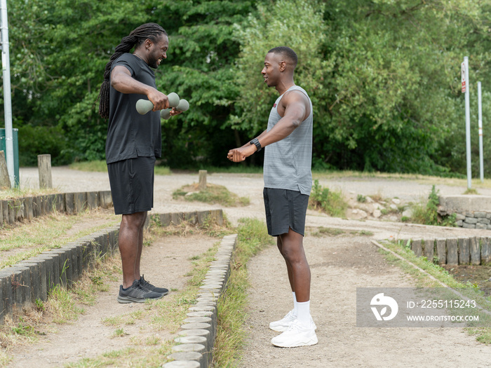 Two men exercising with dumbbells in park