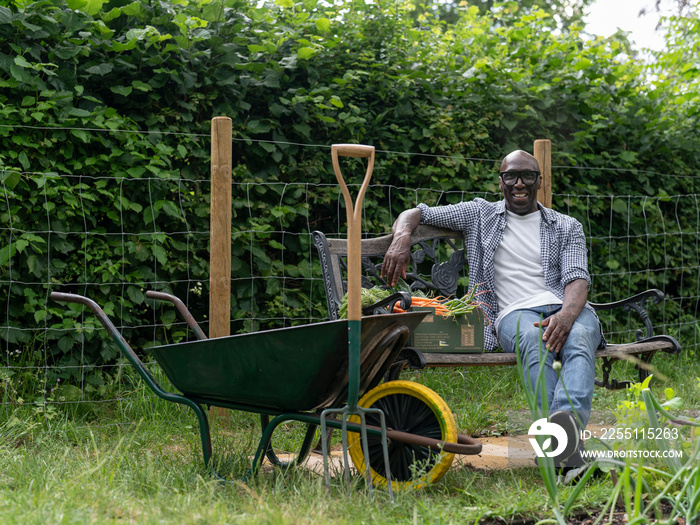 Smiling mature man resting on bench after working in garden