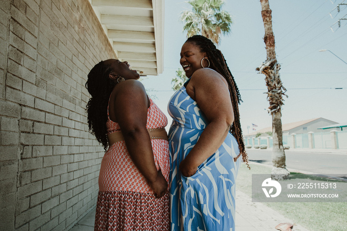 2 plus size African American women stand and laugh on the street