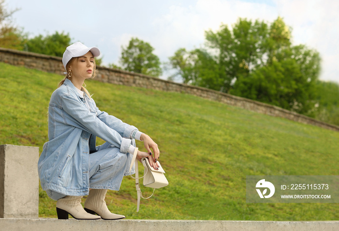 Young pensive woman in baseball cap squatting outdoors