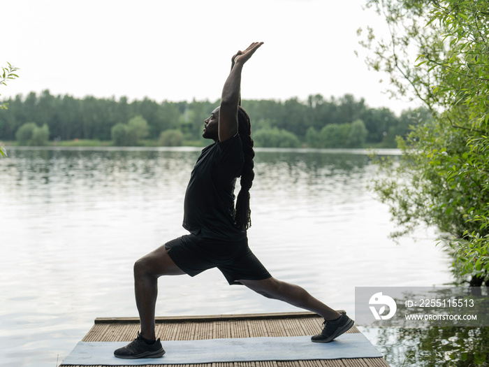 Man practicing yoga by lake