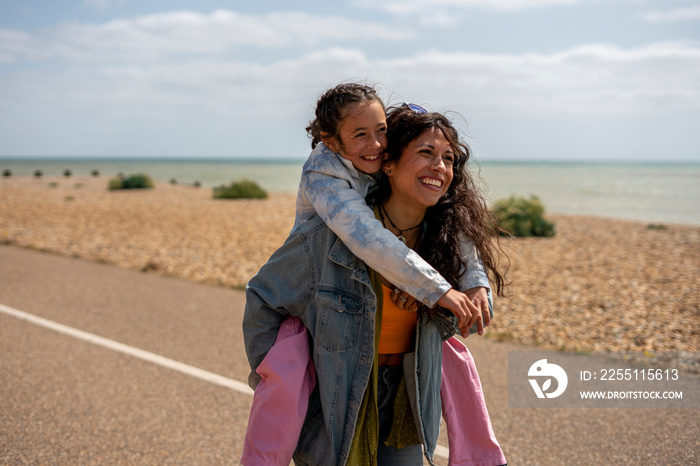 Smiling mother giving daughter (8-9) piggyback ride