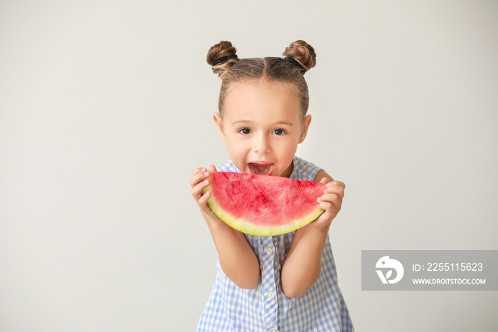 Cute little girl with slice of fresh watermelon on light background