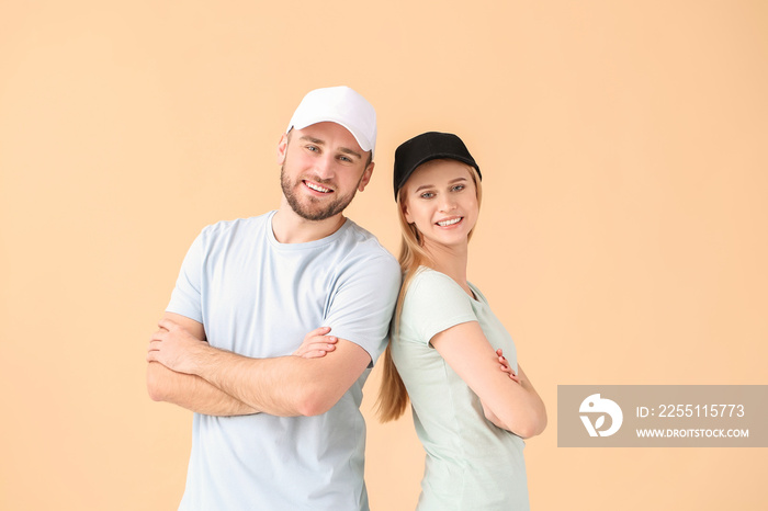 Young couple in stylish caps on color background