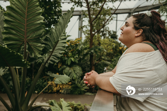 plus size woman leans on railing and looks at plants