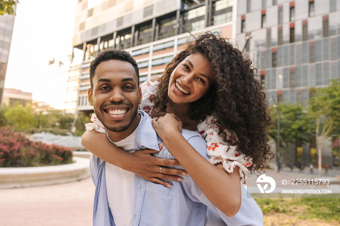 Happy young african guy and girl smiling looking at camera relaxing outdoors. Couple laughing have fun, wear summer clothes. Lifestyle concept