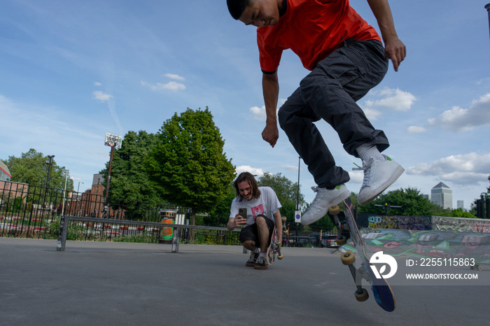 Man recording friend doing skateboard tricks