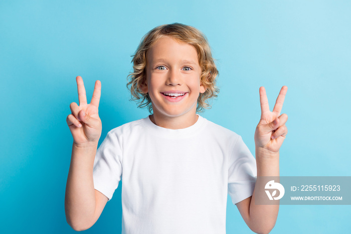 Photo of positive boy make v-sign toothy smiling wear casual style clothes isolated over blue color background