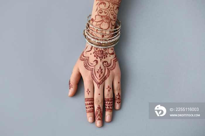 Beautiful female hand with henna tattoo on grey background