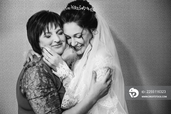 the daughter who became the bride gently embraces her mother on black and white photographs