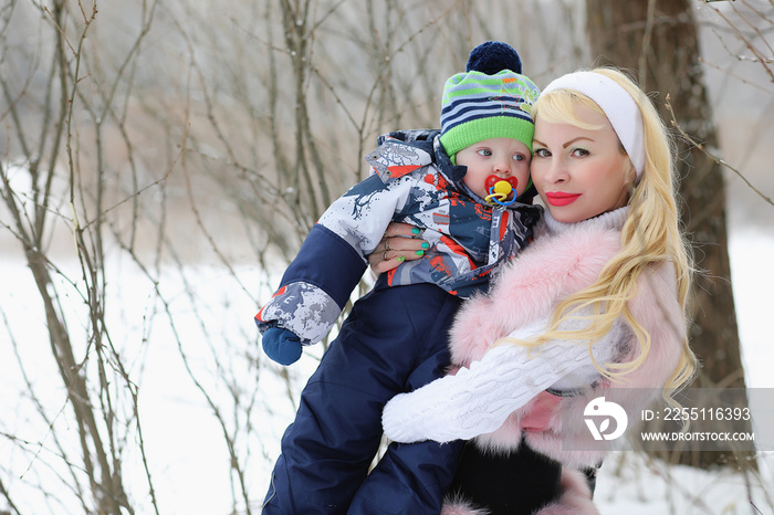 Young mother walks on a winter day with a baby in her arms in the park