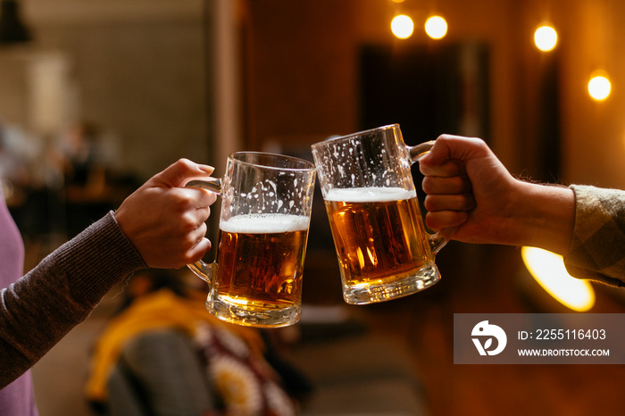 Close-up of two people toasting with beer.