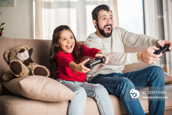 excited father and daughter playing video game at home