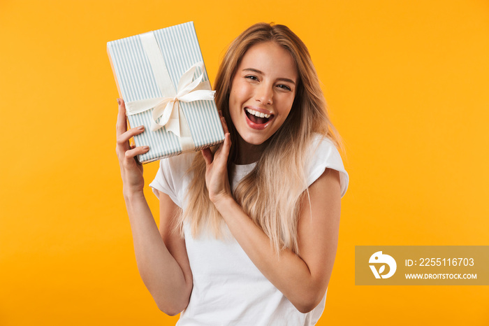 Portrait of an excited blonde young woman holding present