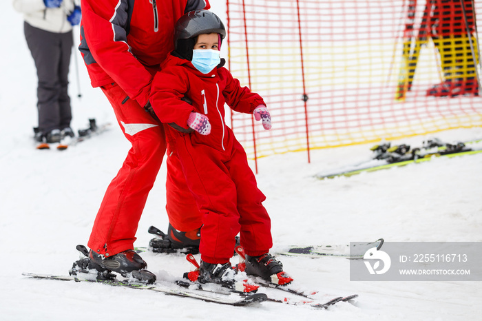 Instructor shows little girl and some exercises on skis