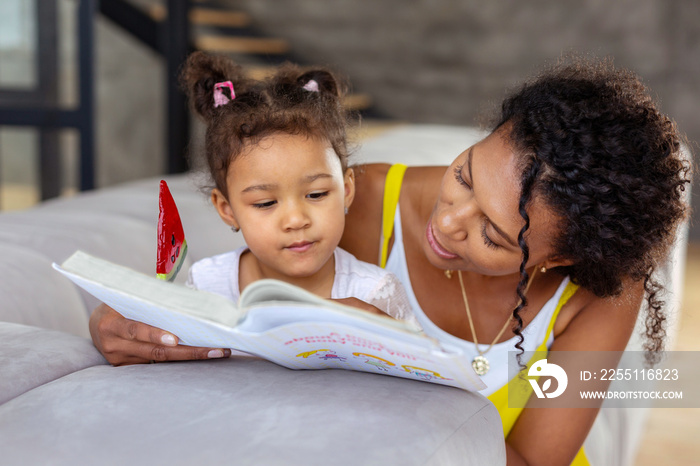 Attentive curly-haired female person looking at her daughter