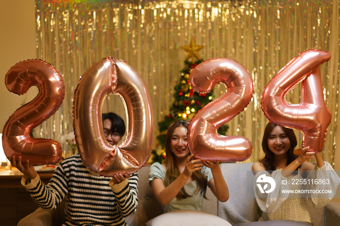 New Year party concept, Group of friends holds balloon air pink gold number 2024 in new year party