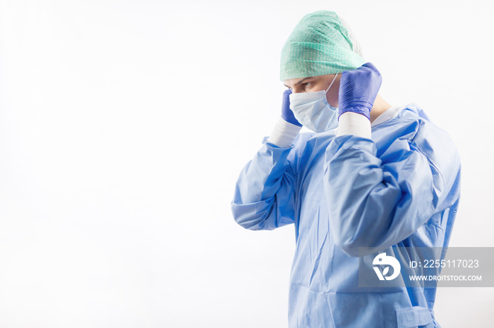 Surgeon doctor in sterile gloves preparing for operation in hospital. He is wearing surgical cap and blue gown