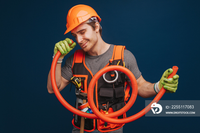 Curious builder is looking inside the trumpet, isolated over blue background