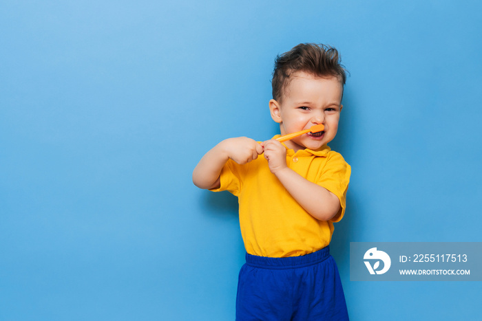 Happy child kid boy brushing teeth with toothbrush on blue background. Health care, dental hygiene. Mockup