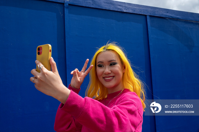 Young woman with yellow hair taking selfie outdoors