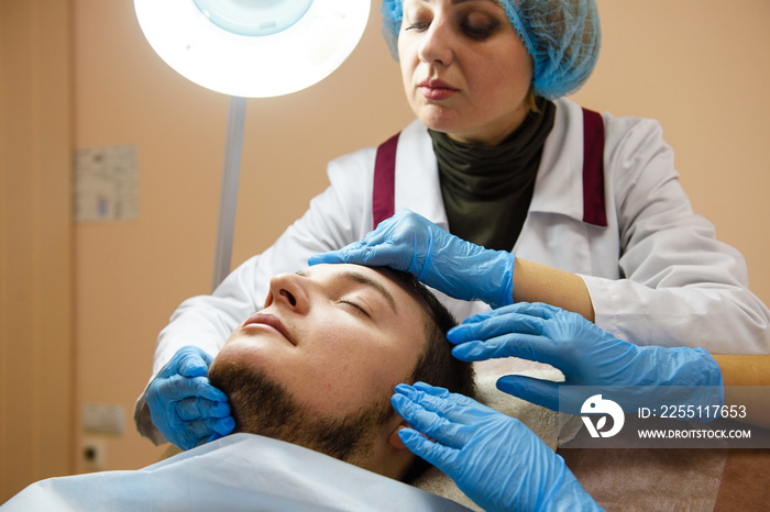 Hands of doctors in rubber blue gloves touch face