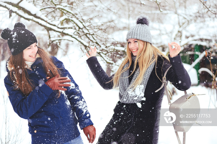 funny and happy two beautiful girlfriends play in the snow in winter, a lot of snow and winter clothes. blonde and brunette emotions