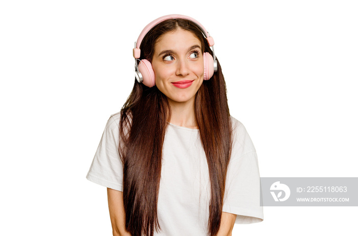 Young caucasian woman wearing headphones isolated dreaming of achieving goals and purposes