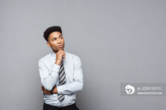 Business Concept - Confident thoughtful young African American holding hand on his chin and thinking about business.