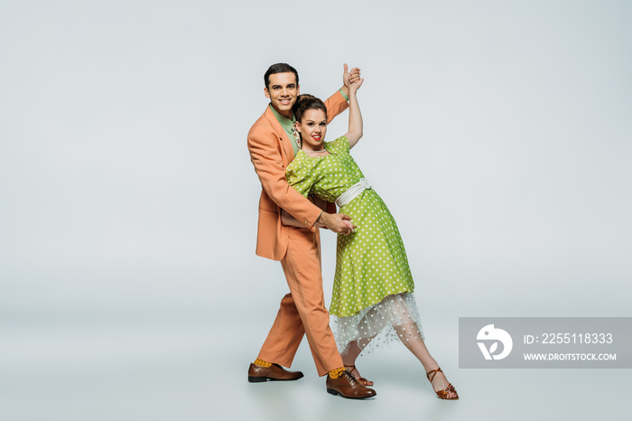 stylish dancers looking at camera while dancing boogie-woogie on grey background