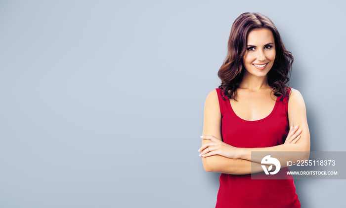 Photo of happy smiling young woman in red casual clothing, against grey wall