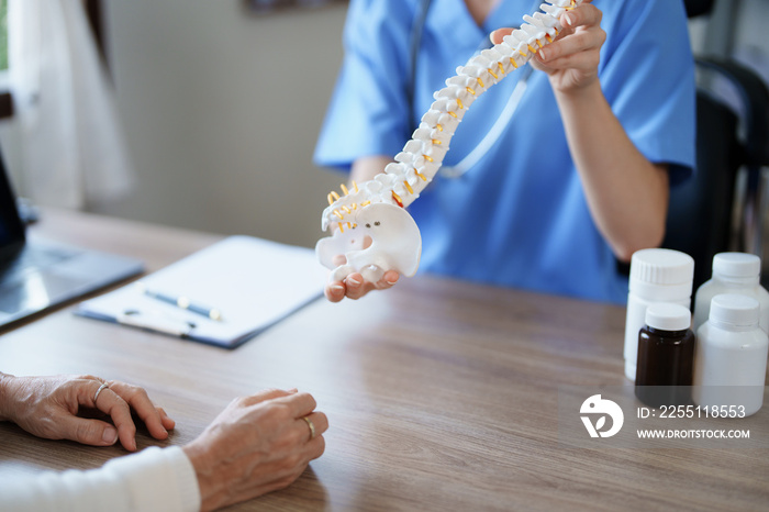 Portrait of a female doctor talking to an elderly patient about herniated disc deterioration from long hours of work.