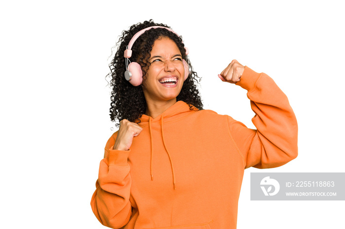 Young Brazilian woman listening to music with headphones isolated raising fist after a victory, winner concept.