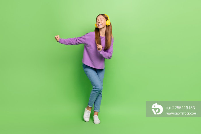 Full size photo of positive optimistic girl with long hairdo dressed denim jeans headphones dancing isolated on green color background