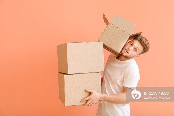 Young man with cardboard boxes on color background