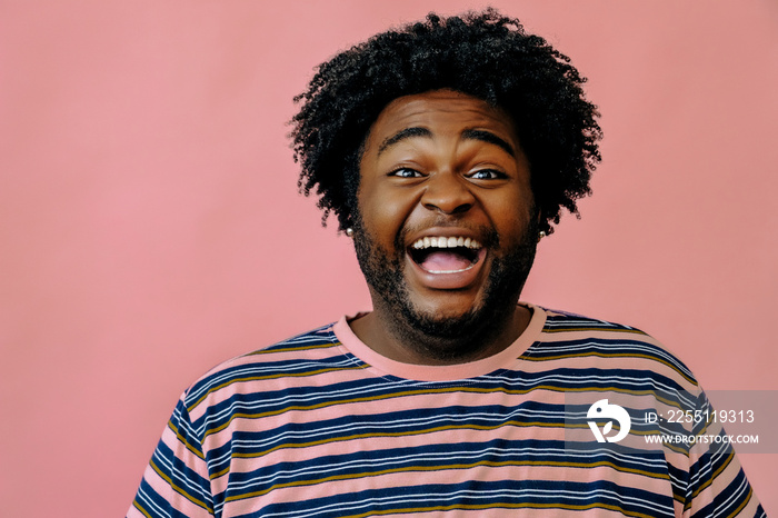 young happy african american man posing in the studio over pink background