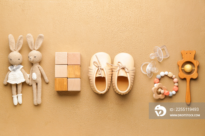 Baby booties with toys on color background