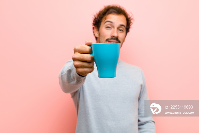 young handsome man with a coffee cup against pink flat wall