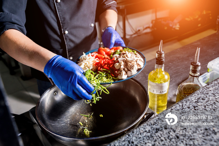 Chef cooking pasta with vegetables in pan. Italian style cuisine. Restaurant.