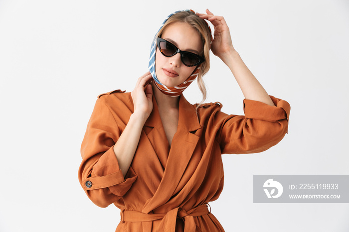 Beautiful young woman wearing silk stylish scarf posing isolated over white wall background wearing sunglasses.