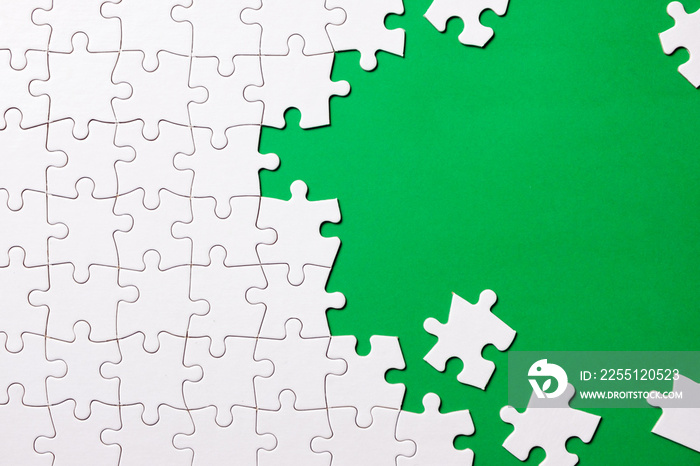 Green background made from white jigsaw puzzle pieces and place for your content