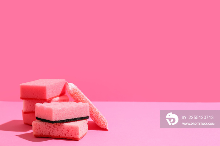 Pink cleaning sponges on color background