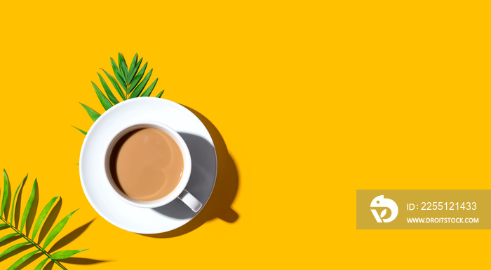 A cup of coffee with tropical leaves - flat lay