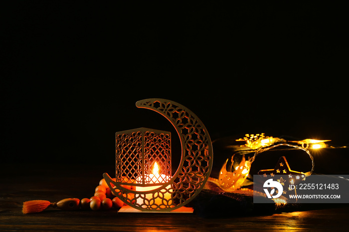 Arabic candle holder with glowing candle, garland and tasbih on dark background