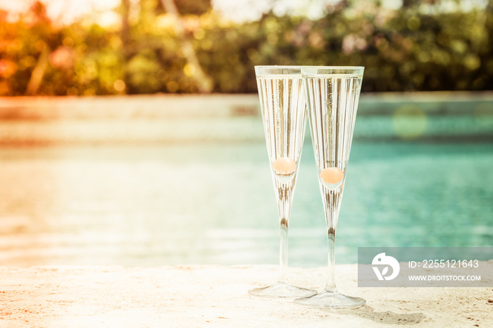 Two glasses of prosecco cocktail with orange berry at the edge of a resort pool. Concept of luxury vacation