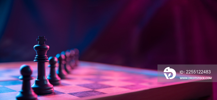 Chess pieces on a chessboard on a dark background shot in neon pink-blue colors. The figure of a chess .Close up.